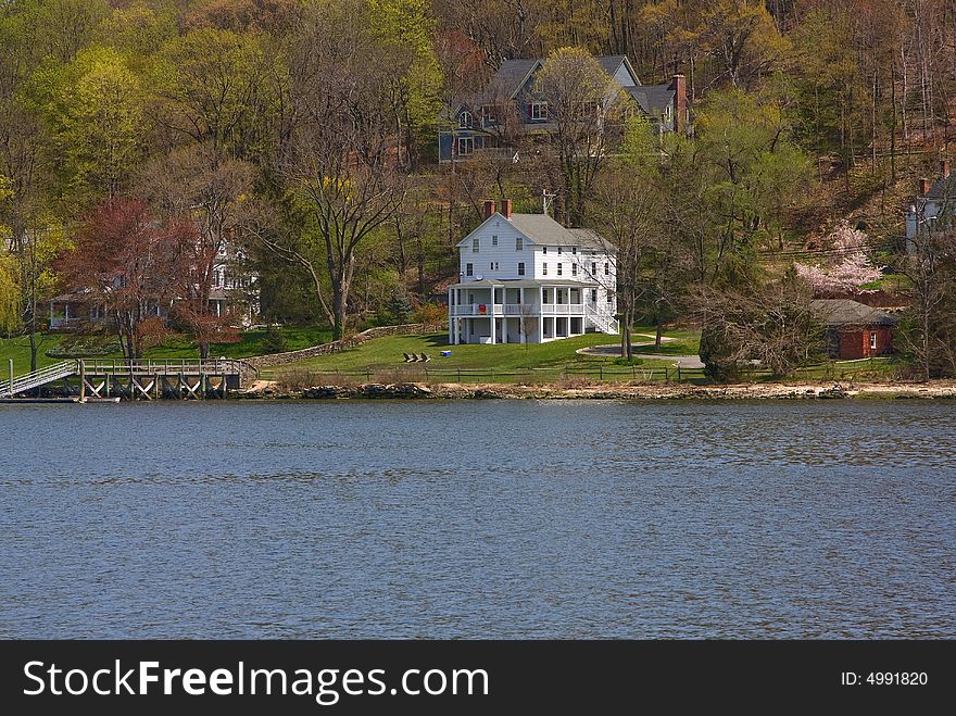 A remotely located white Victorian/Colonial mansion on the water and in the woods on a spring day. A remotely located white Victorian/Colonial mansion on the water and in the woods on a spring day.