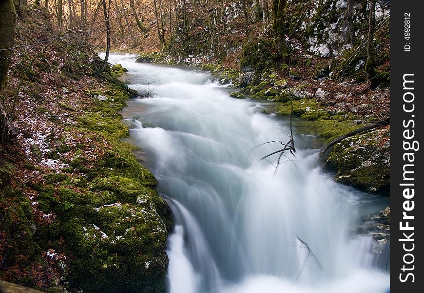 Mountain stream flowing over rocky ground making cascades.