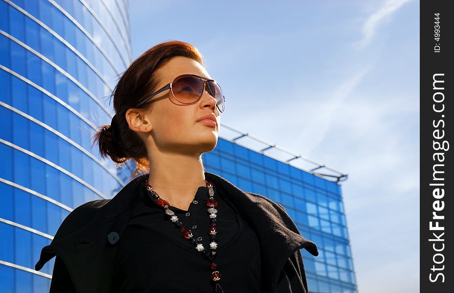 Beautiful young brunette. Modern building behind her