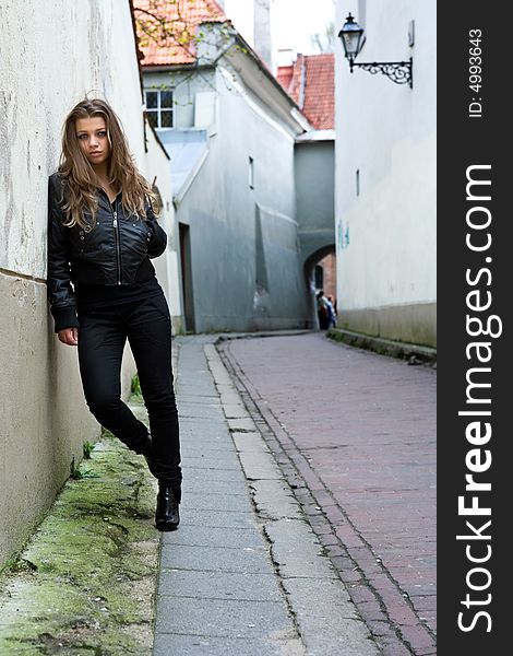 Portrait of the girl near wall in an old town