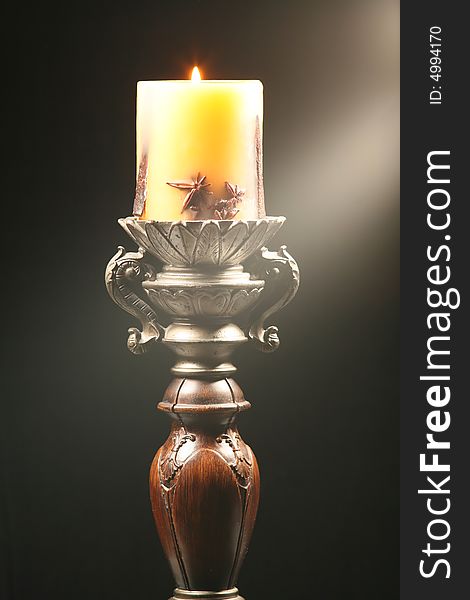 Antique wooden candlestick with ray of light isolated on black background