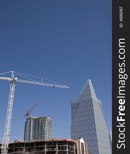 A white construction crane over a new high-rise tower going up. A white construction crane over a new high-rise tower going up