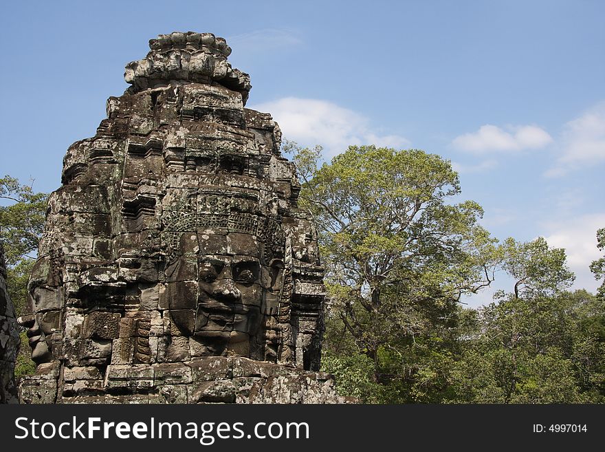 UNESCO heritage site Angkoro Temples in Cambodia. Bayon temple. face of idol with the trolpical jungle as background. UNESCO heritage site Angkoro Temples in Cambodia. Bayon temple. face of idol with the trolpical jungle as background