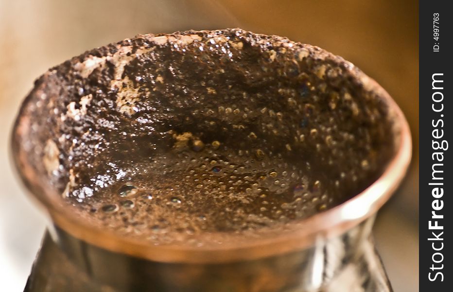 Close-up of copper cezve with boiled over black coffee. Close-up of copper cezve with boiled over black coffee