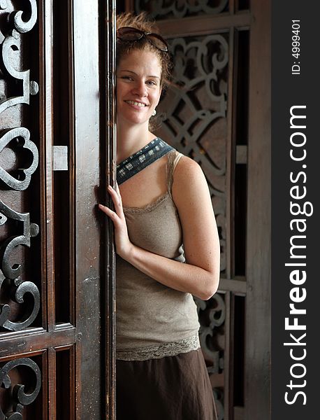 Happy woman leaning on a carved wooden door.