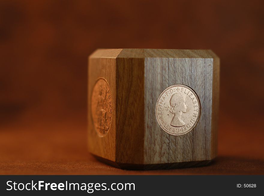 A wooden paperweight with British coins imbedded in four sides. A wooden paperweight with British coins imbedded in four sides.