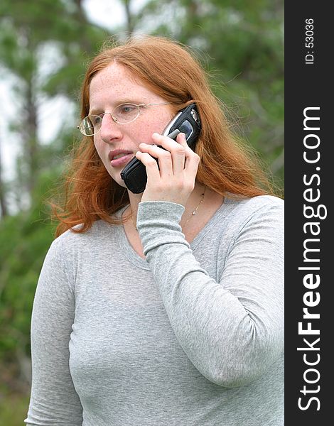 A redheaded woman in a gray long sleeved shirt gets some bad news on the phone. A redheaded woman in a gray long sleeved shirt gets some bad news on the phone.