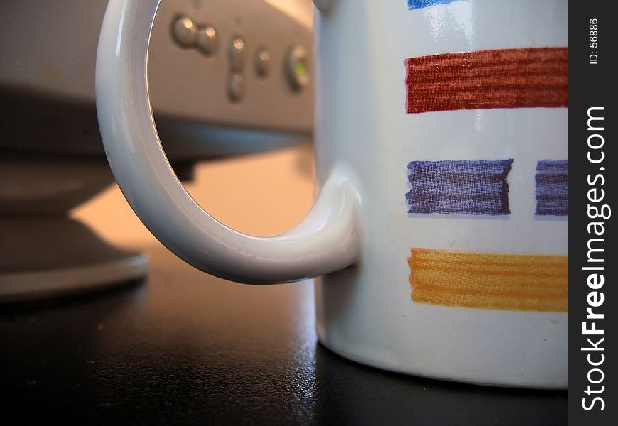 Monitor controls seen through handle of coffee mug, focus on mug. Monitor controls seen through handle of coffee mug, focus on mug
