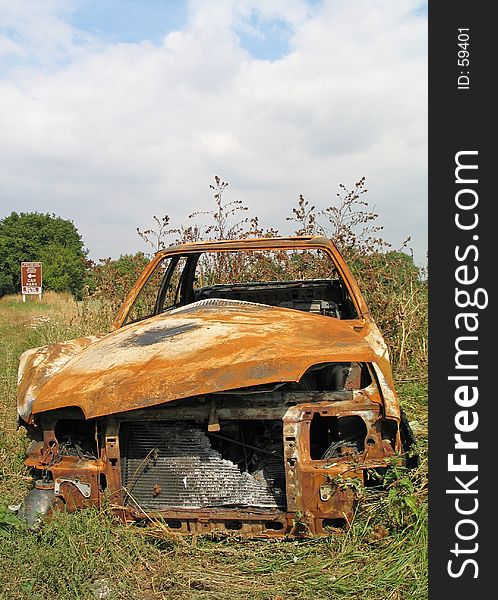 The front view of a burnt out rusted old car dumped by the side of the road. The front view of a burnt out rusted old car dumped by the side of the road.