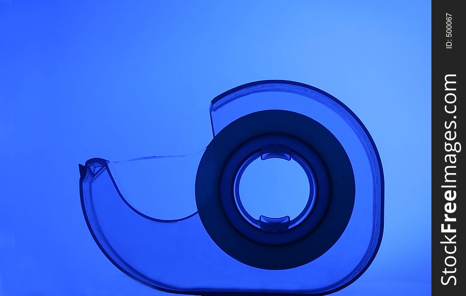 Transparent tape dispenser on blue background. Transparent tape dispenser on blue background