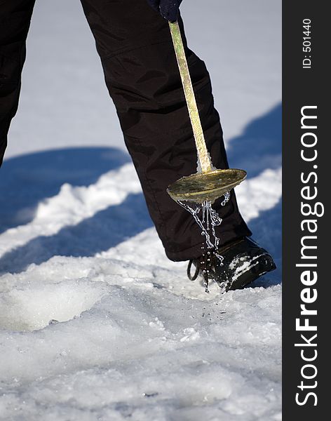 Ice fisherman dipping ice out of ice hole. Ice fisherman dipping ice out of ice hole