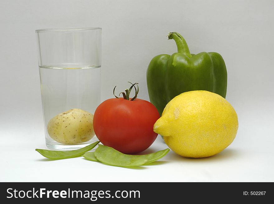 Green paprika, red tomat, yellow lemon and a glass of water. Green paprika, red tomat, yellow lemon and a glass of water.