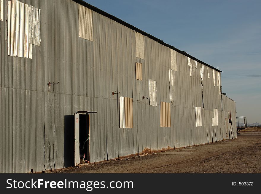 Abandoned Warehouse with open side door. Past repair work can be clearly seen.