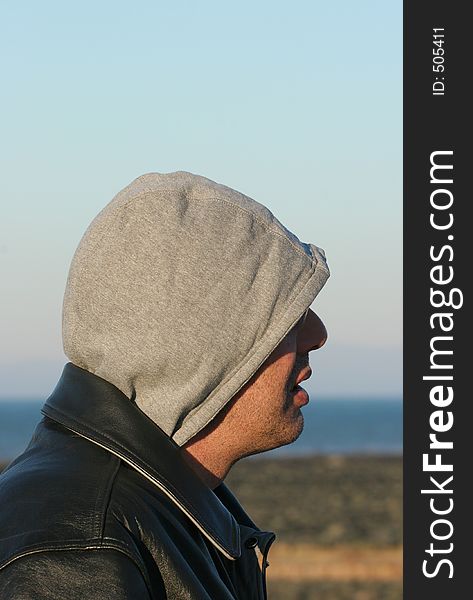 Profile of a man wearing a leather jacket and a hood. Profile of a man wearing a leather jacket and a hood.