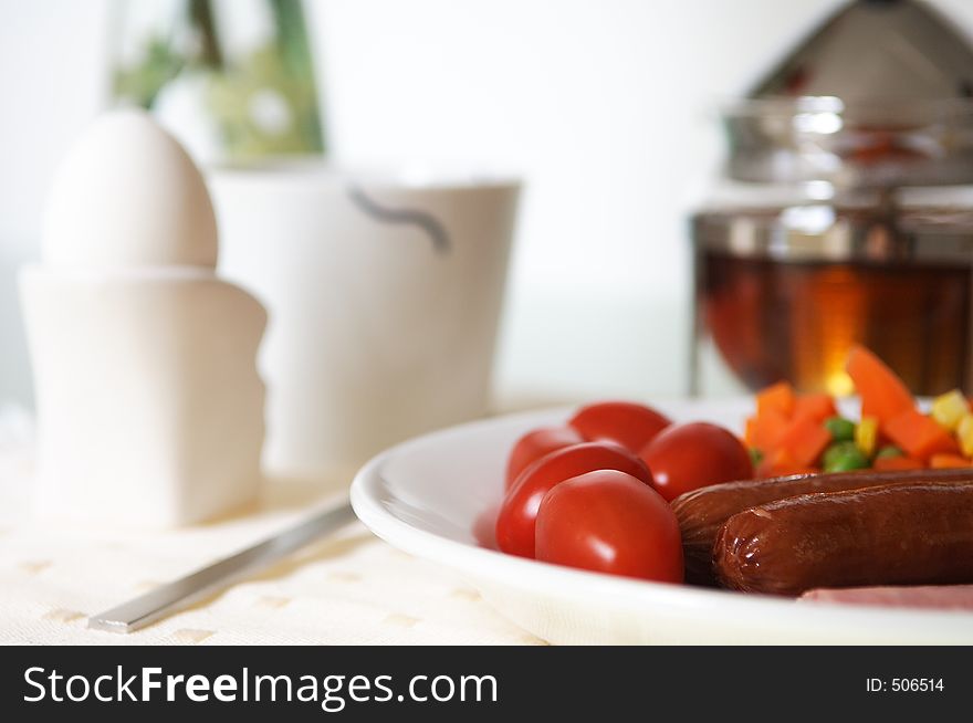 Breakfast with eggs sausage and tea in a white background