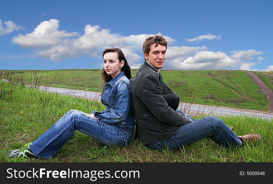 Guy and girl sits on a grass on a background of the sky. Guy and girl sits on a grass on a background of the sky