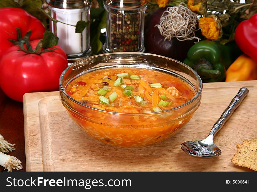 Bowl of Chicken Tortilla Soup garnished with shredded cheddar and green onions.