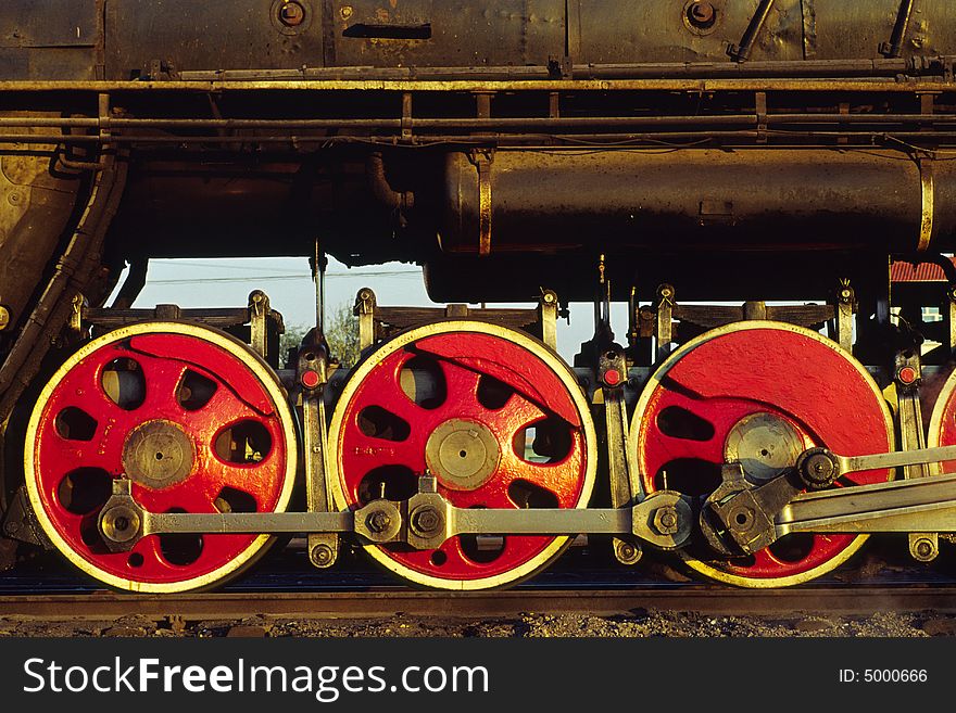 Team train on the railway. dark body and red wheels in golden sunlight. Team train on the railway. dark body and red wheels in golden sunlight