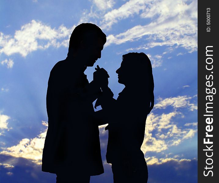 Two silhouettes. The enamoured guy and the girl on a background of the sky