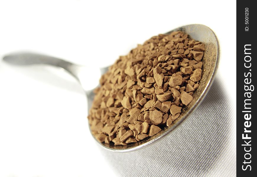 Instant coffee brown granules closeup and metal spoon. Instant coffee brown granules closeup and metal spoon