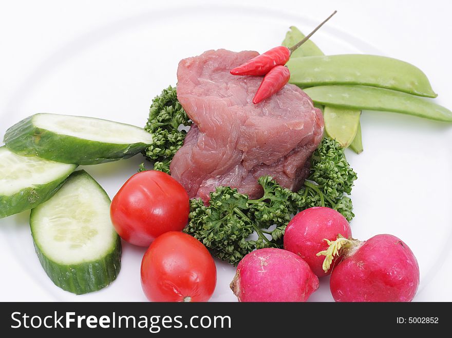 Vegetables and raw meat on a plate. Isolated on a white background