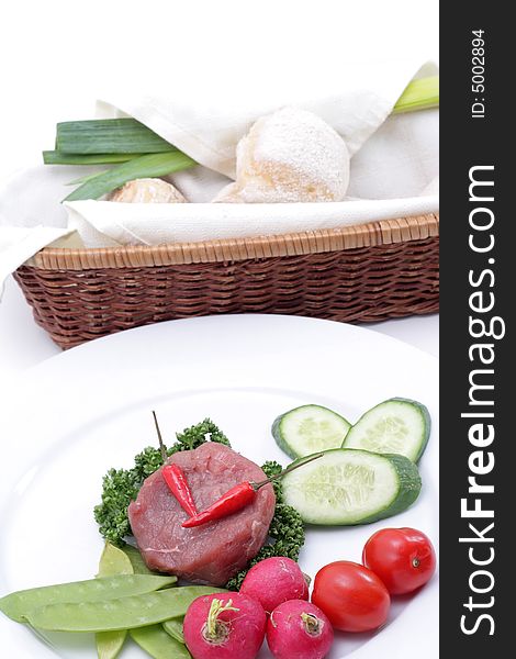 Vegetables and raw meat on a plate. Isolated on a white background