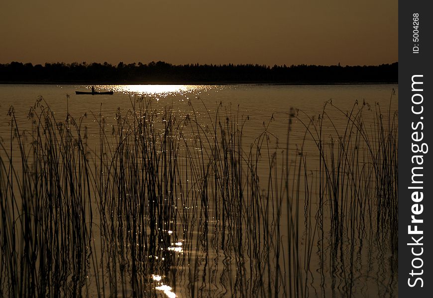 Silhouette canoe paddling across lake. Silhouette canoe paddling across lake