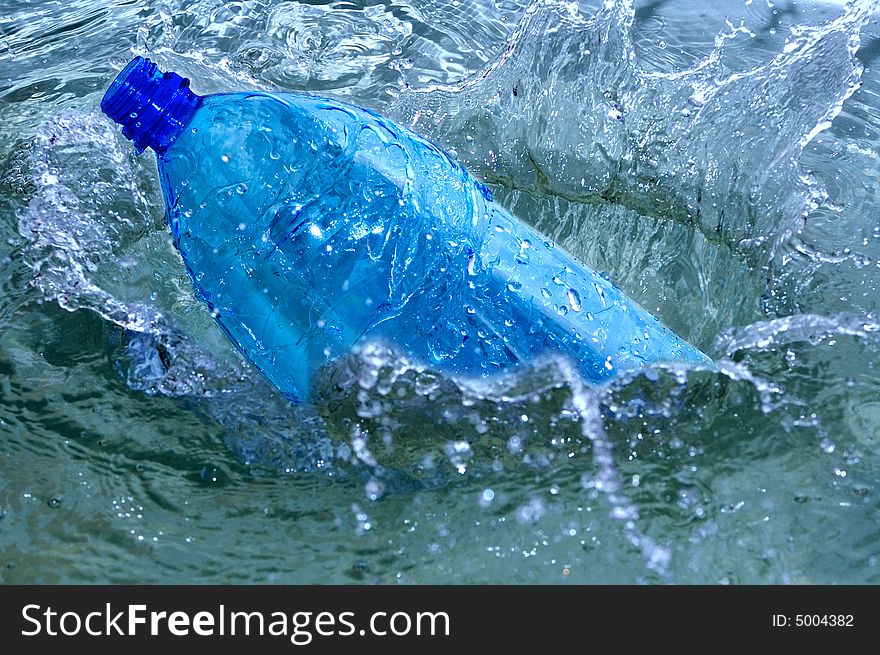Falling bottle in blue water splash