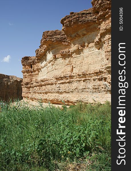 Desert rock, blue sky, green grass