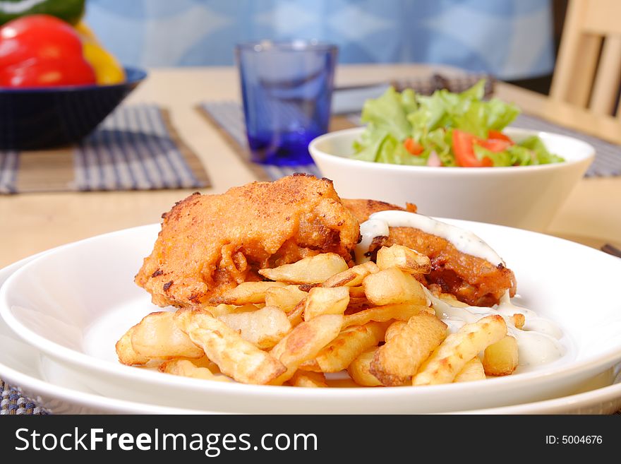 French fries and chicken legs on the plate with garlic sauce