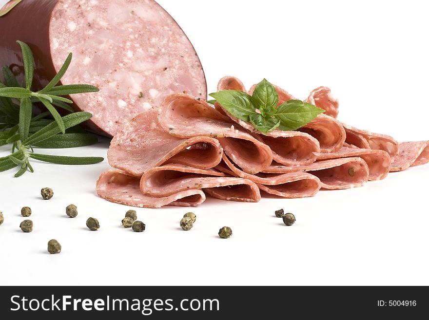 Salame and slices of salame with basil and rosemary. Salame and slices of salame with basil and rosemary