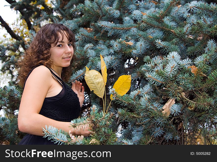 Young beautiful woman standing near spruce tree and smiling