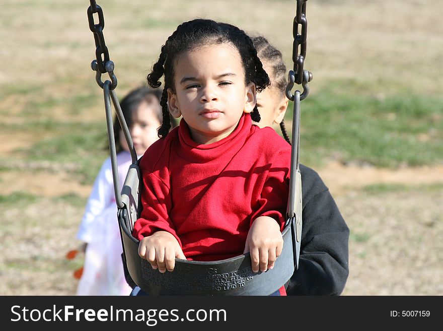 Toddler being pushed on the swing at the playground
