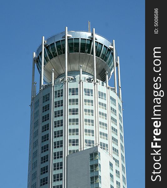 Corporate multi-storey building - a tower on a background of the dark blue sky in a bright sunny day. Corporate multi-storey building - a tower on a background of the dark blue sky in a bright sunny day