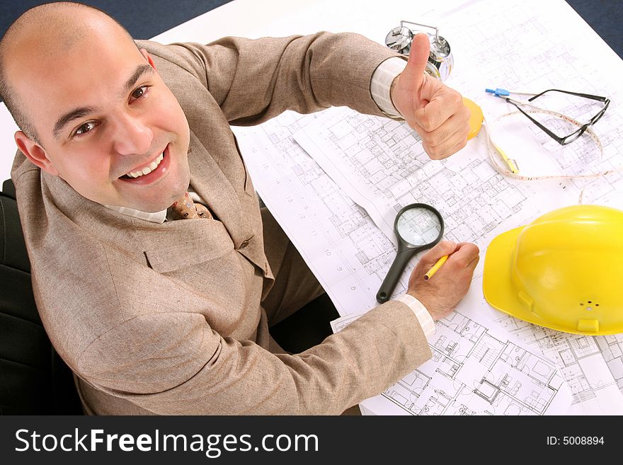 A businessman happiness with architectural plans at desk