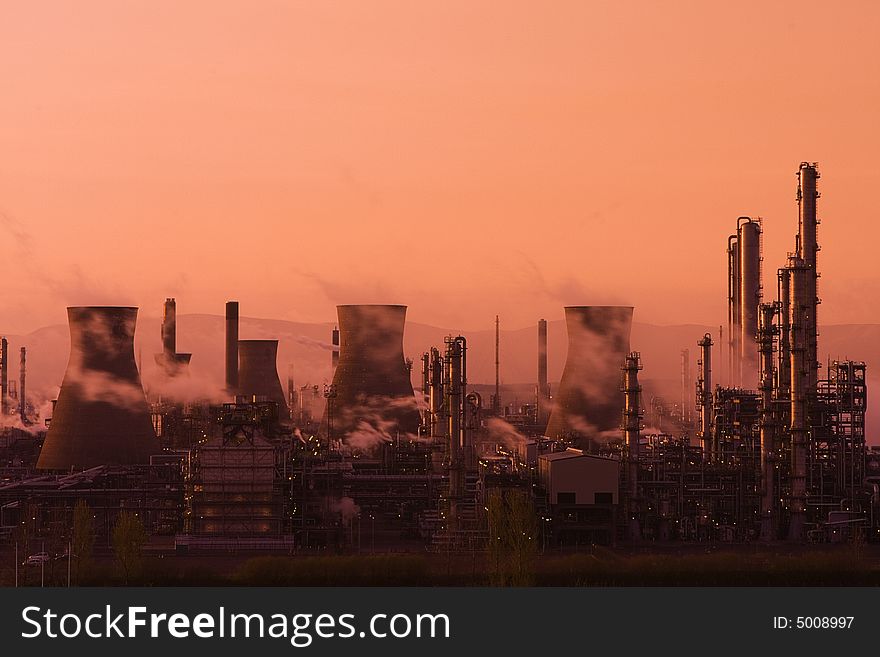 A view of the smoking chimney stacks of Grangemouth Oil Processing Plant/Refinery at sunset. A view of the smoking chimney stacks of Grangemouth Oil Processing Plant/Refinery at sunset.