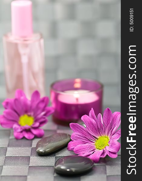 Spa stones, fragrance bottle, flowers and candle on grey background. Spa stones, fragrance bottle, flowers and candle on grey background