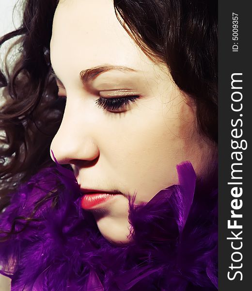 A portrait about a pretty lady with white skin, long brown wavy hair and a scarf made with vivid purple feathers. A portrait about a pretty lady with white skin, long brown wavy hair and a scarf made with vivid purple feathers