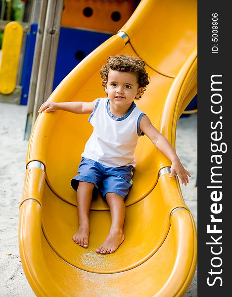 A cute young kid playing on a slide in a park. A cute young kid playing on a slide in a park