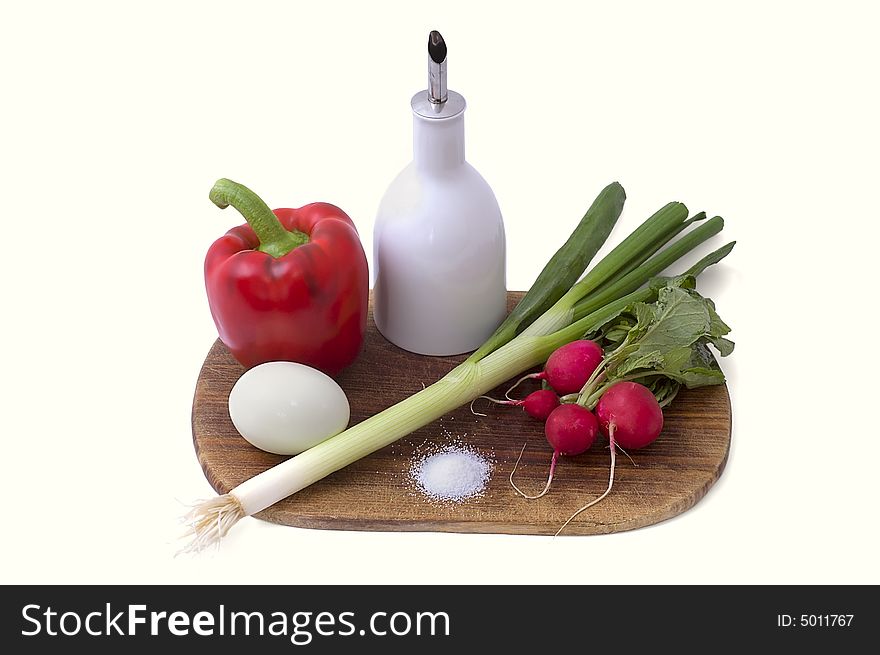 Still-life on a wooden hardboard with garden radish, paprika, onion and egg isolated on white.