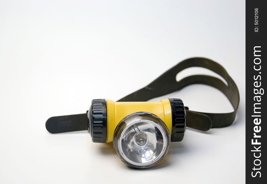 A yellow flashlight headlamp on a white background. A yellow flashlight headlamp on a white background.