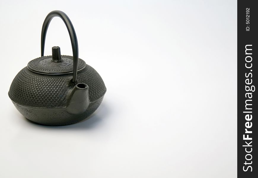 A small cast iron teapot on a white background. A small cast iron teapot on a white background.