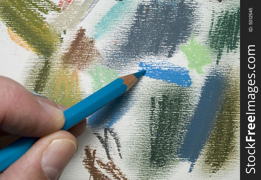 Fingers drawing with a crayon on a sheet of paper with 
colour patterns. Fingers drawing with a crayon on a sheet of paper with 
colour patterns