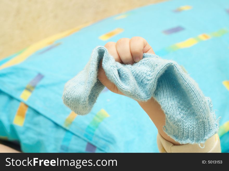 The hand of the child compresses a blue sock. The hand of the child compresses a blue sock