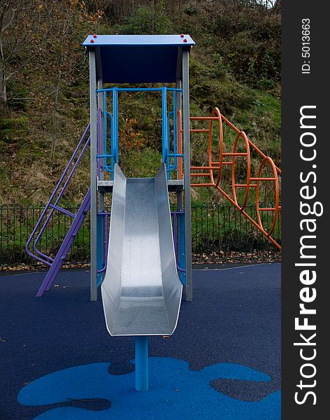 Photo of a childrens playground slide with a safety mat covering the ground