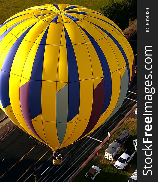 Yellow hot air balloon flying over road viewed from above. Yellow hot air balloon flying over road viewed from above