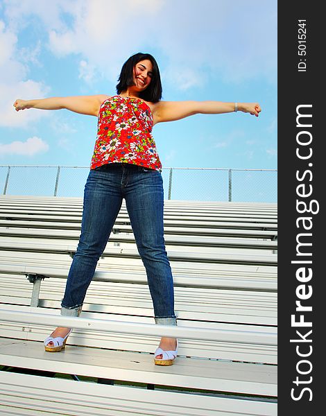 Woman in a cheer leading pose on the bleachers. Woman in a cheer leading pose on the bleachers
