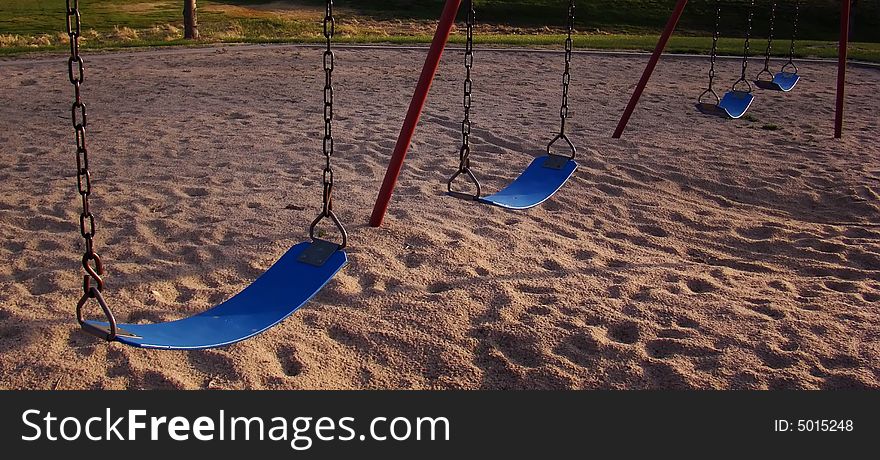 Blue seats of swing set on playground in small Midwestern city park. Blue seats of swing set on playground in small Midwestern city park