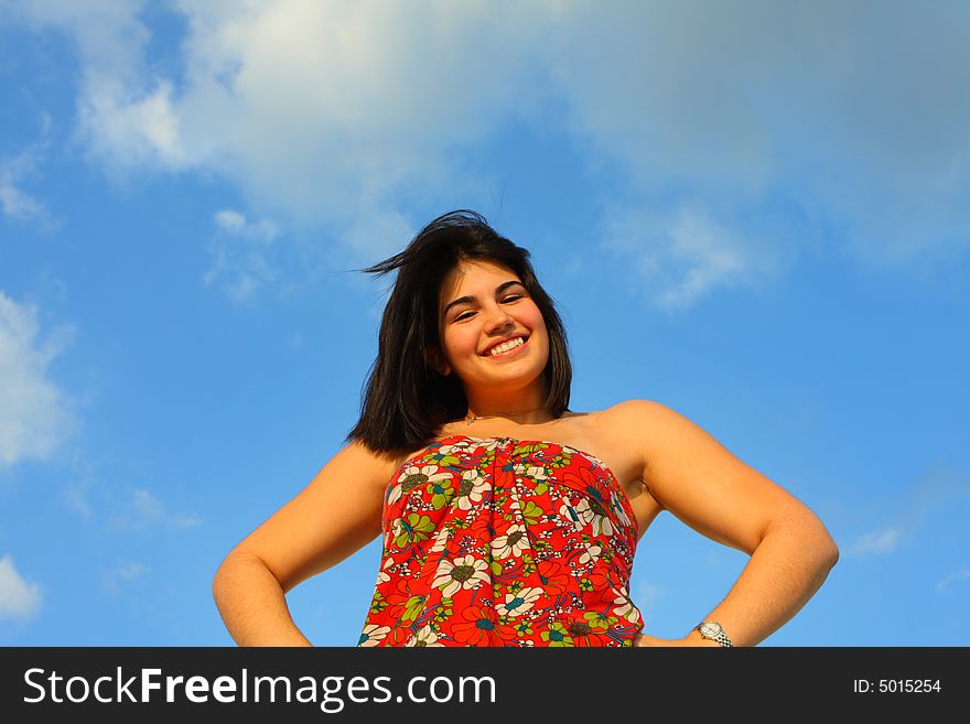 Woman with arms at her hips and a blue sky in the background. Woman with arms at her hips and a blue sky in the background