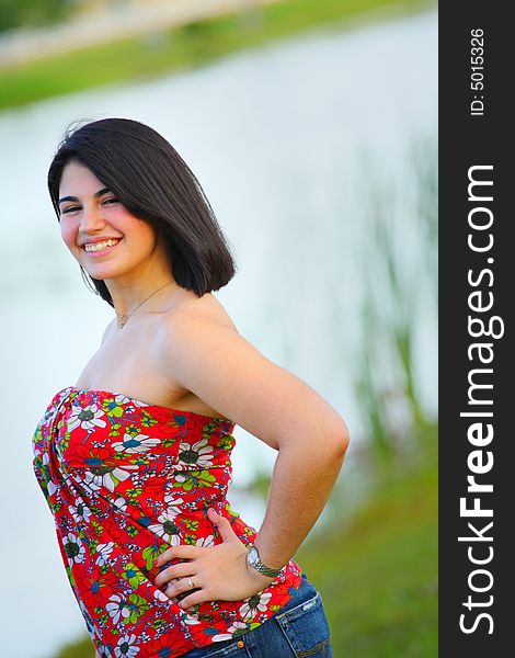 Woman standing by a pond smiling. Woman standing by a pond smiling